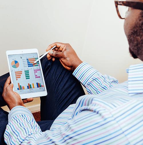 One man sitting down, viewing financial charts on a tablet on his lap